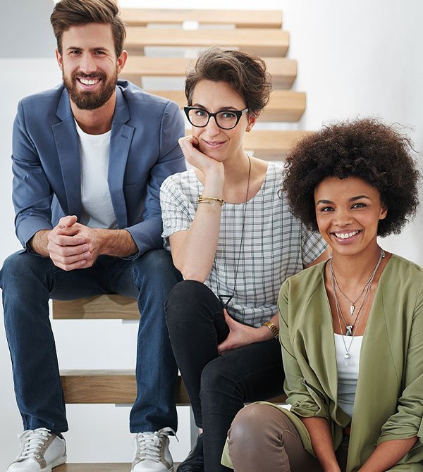 Professional IT team of three people sitting on stairs